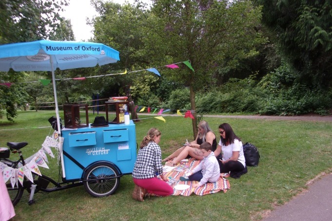 A group of people participating in an arts activity in front of the Museum Tricycle at Cutteslowe Park