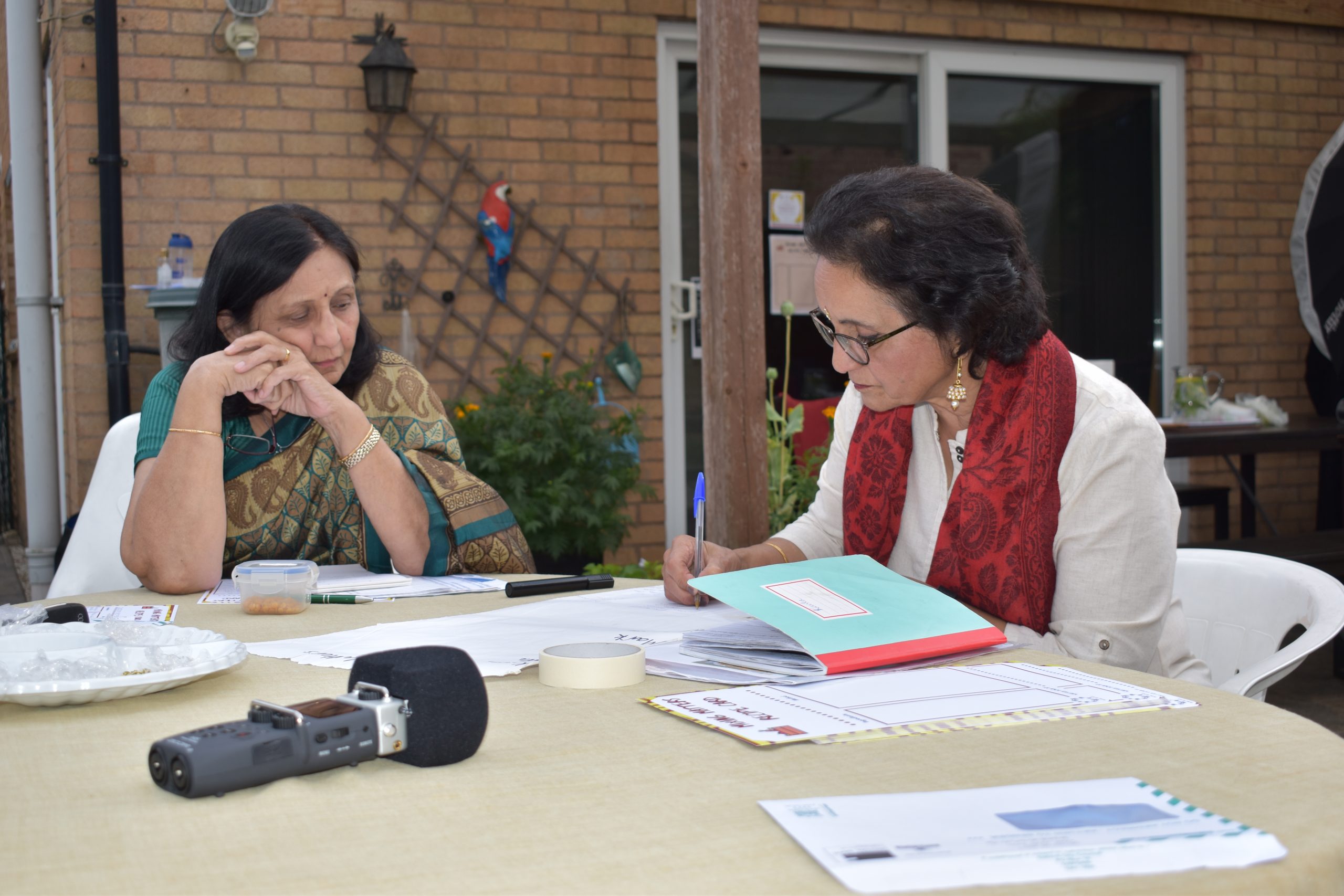 A photo of two women swapping recipes with their conversation being recorded.
