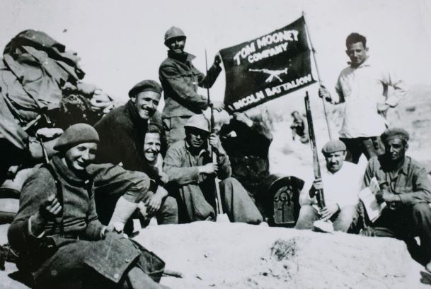 Black and white photograph of a battalion of men holding a banner. 
