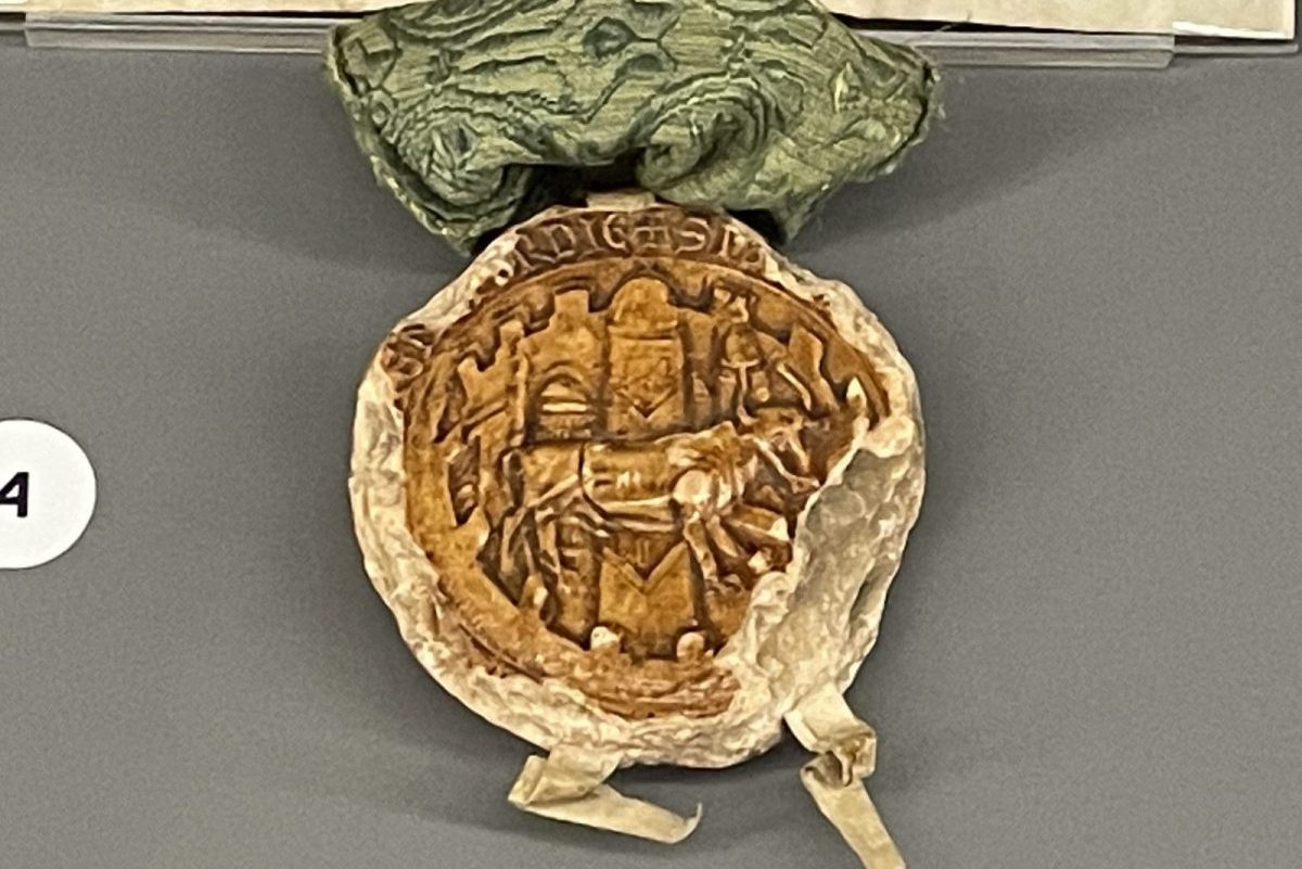 Orange coloured circular seal depicting a walled city, including three towers, an ox walking from left to right and the assertive legend (in Latin): ‘The common seal of all the citizens of the City of Oxford.