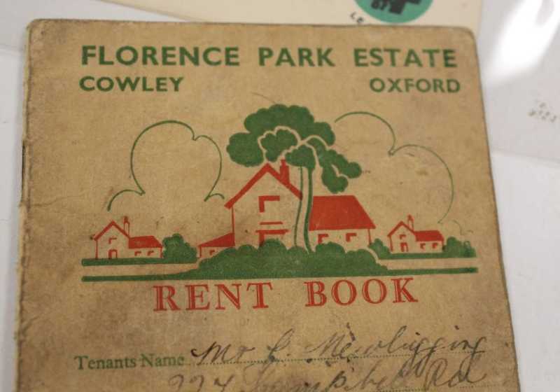 The top half of a rent book, printed on paper that is brown with age. A graphic design on the front shows houses, trees and shrubbery. Printed writing above the design reads: 'Florence Park Estate, Cowley, Oxford'.