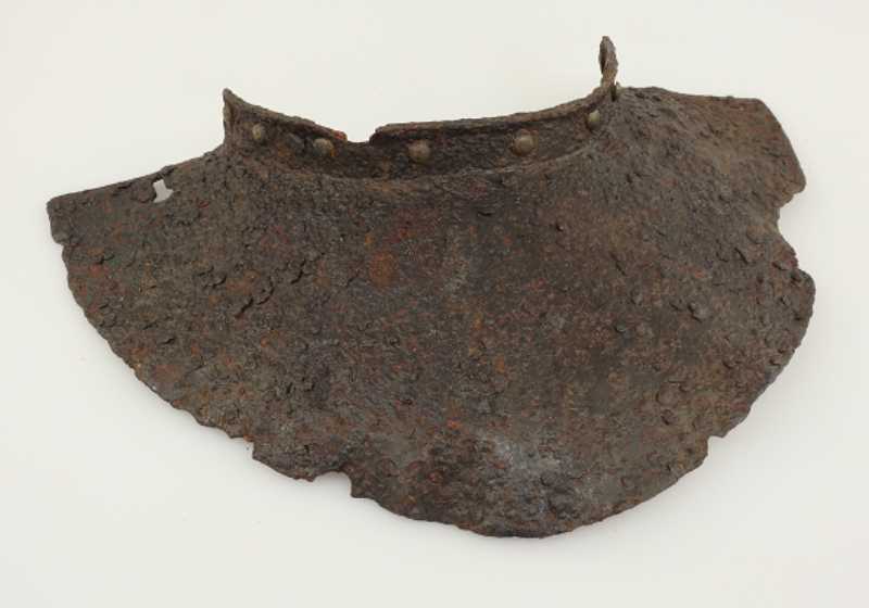 A corroded metal piece of armour designed to cover the throat and chest.
