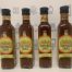 Four bottles containing brown liquid with a yellow label printed with Oxford Sauce